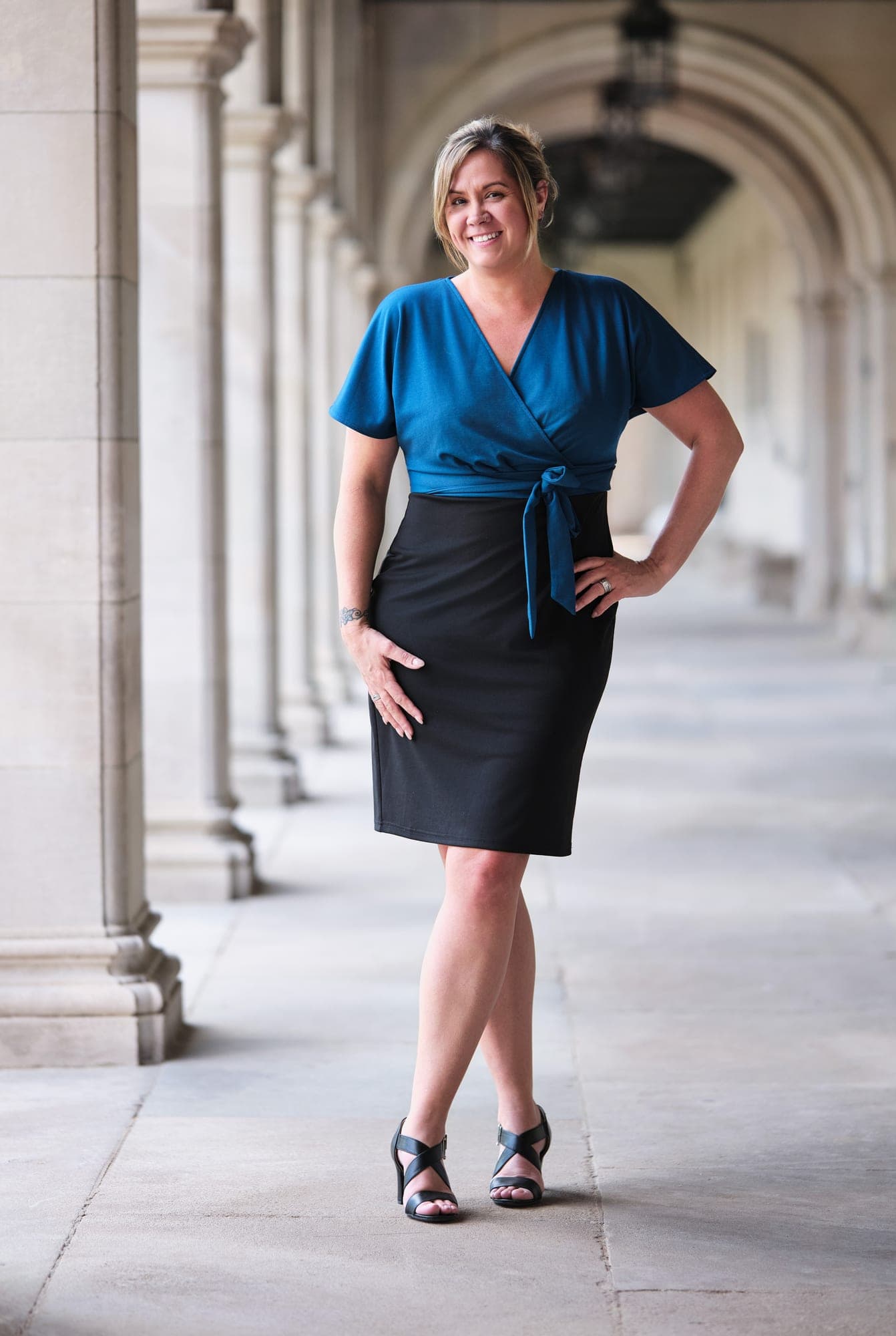 Executive in a teal wrap top and dark pencil skirt in a limestone arcade in St. Louis, by Henry David Photography